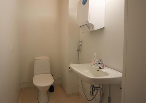a white bathroom with a toilet and a sink at Forenom Hostel Röykkä in Helsinki