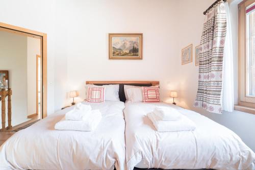 two beds in a bedroom with white sheets and pillows at Chalet Ulysse in Zermatt