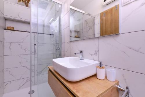 ein weißes Badezimmer mit einem Waschbecken und einem Spiegel in der Unterkunft Sun in Mali Lošinj