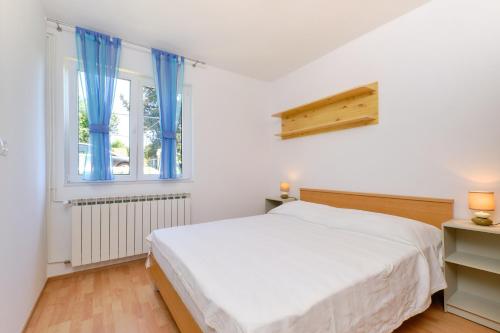 a white bedroom with a bed and a window at Sun in Mali Lošinj