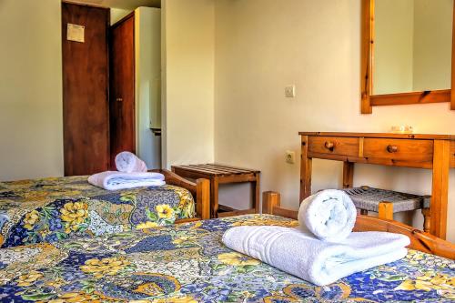 two beds in a room with towels on them at Hotel Benitses Arches in Benitses