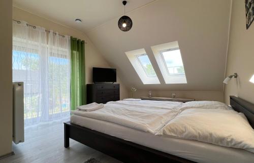 a bedroom with a large bed with two windows at Gardencity Apartmanház in Győr