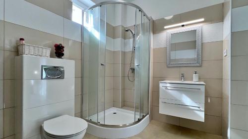 y baño con ducha, aseo y lavamanos. en Gardencity Apartmanház en Győr