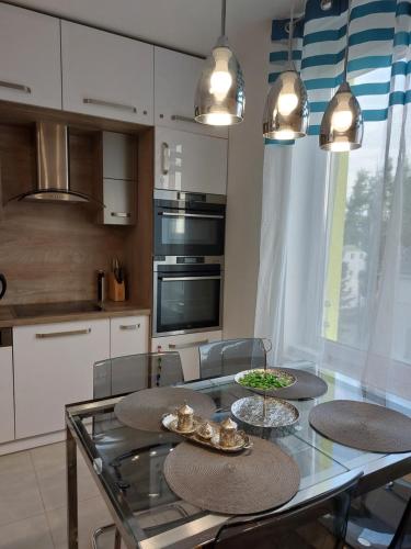 una cocina con una mesa de cristal con 4 platos. en Happiness Apartman, en Kecskemét