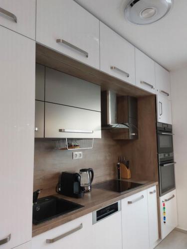 a kitchen with white cabinets and a sink at Happiness Apartman in Kecskemét