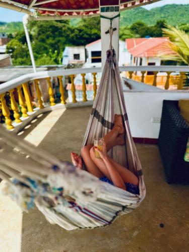 a woman sitting in a hammock with a drink at CASA MOSAICO in Puerto López