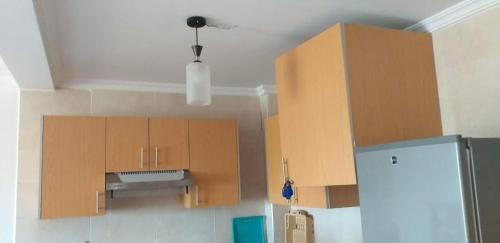 - une cuisine avec des placards en bois et un réfrigérateur dans l'établissement Marina golf assilah مارينا كولف أصيلة, à Assilah