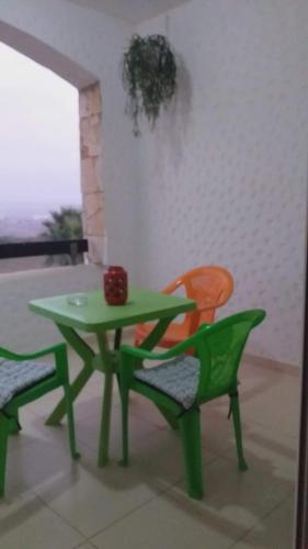 une table verte, 2 chaises, une table et des chaises dans l'établissement Marina golf assilah مارينا كولف أصيلة, à Assilah