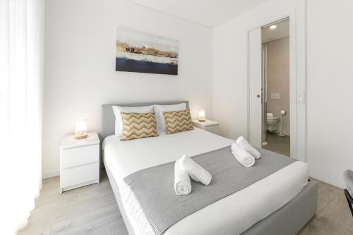 a white bedroom with a large white bed with towels at Blissful Beach Getaway in Nazaré