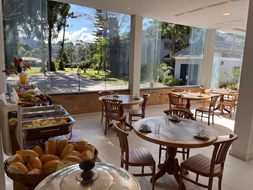 a restaurant with tables and chairs and a buffet of food at Pousada Granja Santa Barbara in Petrópolis