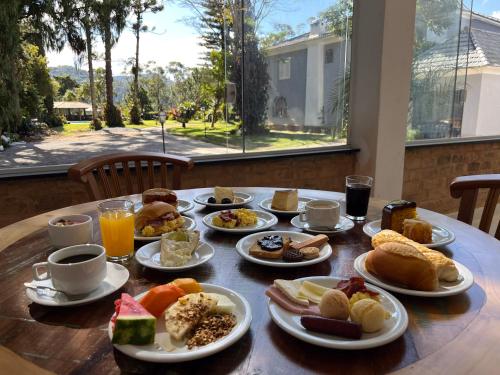 una mesa de madera con platos de desayuno. en Pousada Granja Santa Barbara, en Petrópolis