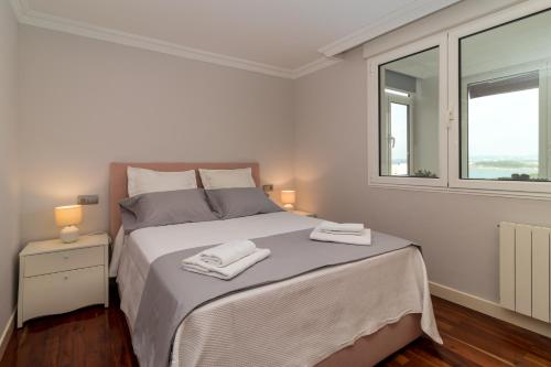 a white bedroom with a bed with two towels on it at El Balcón de Charles in Santander
