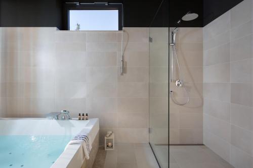a bathroom with a tub and a shower with a glass door at Park Hill Residences in Rabac
