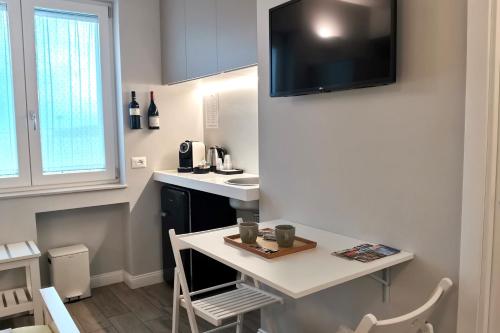 a small kitchen with a table and a tv on the wall at Vicolo Fiore Affittacamere II in Matera