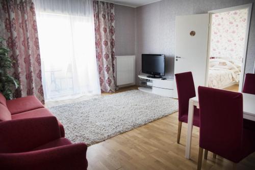 een woonkamer met een tv en een tafel en stoelen bij Aleksandria Apartment in Pärnu