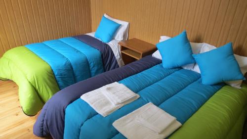 two beds with blue and green pillows in a room at Alojamento Local Duarte's in Coimbra