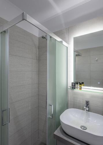 a bathroom with a sink and a shower with a mirror at Milos Bay View in Zefiría