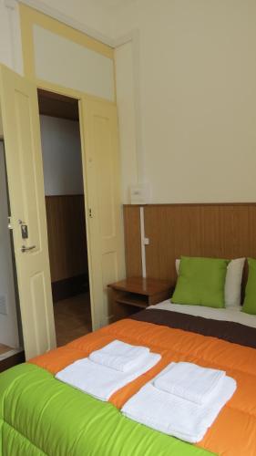 a bedroom with a bed with green and white sheets at Alojamento Local Duarte's in Coimbra