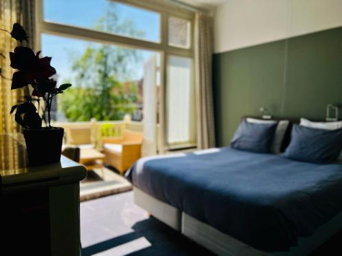 Un dormitorio con una cama azul y una ventana en Bed and Breakfast Juliana, en Eindhoven