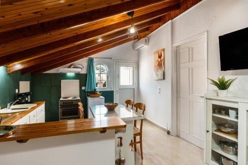 a kitchen with white cabinets and a wooden ceiling at Attico Verde in Kastanéa