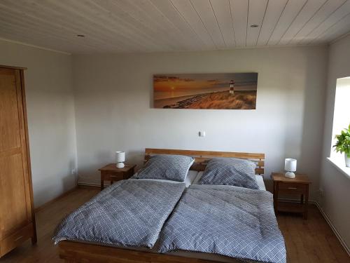 SörupにあるFerienhaus Landlebenのベッドルーム1室(ベッド2台付)が備わります。壁には絵画が飾られています。