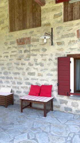 two red pillows sitting on a bench in front of a building at Fienile Chiaramada in Belluno