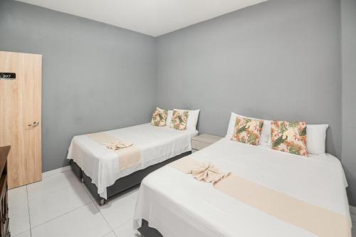 two beds in a small room with white walls at Hotel París in Villeta