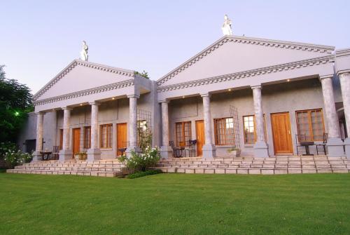 a large white building with orange doors and a yard at Ancient Emperor Guest Estate in Potchefstroom