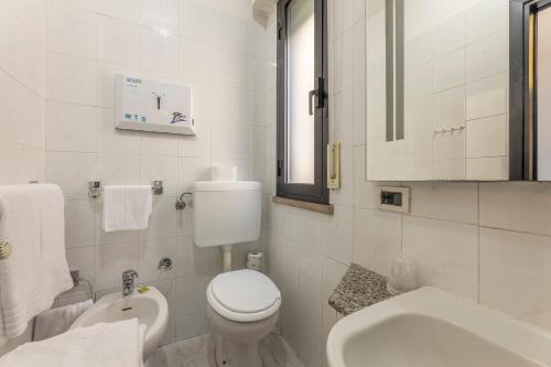 a white bathroom with a toilet and a sink at Hotel Quisisana in Vada
