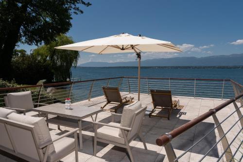 a table and chairs with an umbrella on a deck at Park Villa Geneva - Swiss Hotel Apartments in Geneva