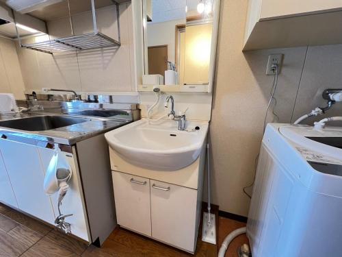 eine kleine Küche mit Spüle und Waschmaschine in der Unterkunft 東横のヨコ in Okayama