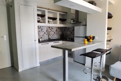 una cocina con armarios blancos, mesa y taburetes en La casa sulla Terrazza, en Sarnico