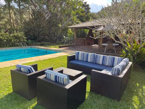 un patio trasero con 2 sofás y una piscina en Pousada Granja Santa Barbara, en Petrópolis
