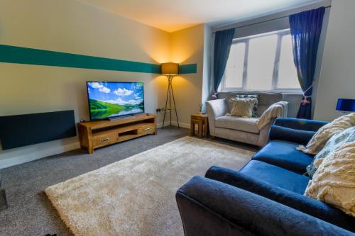 a living room with a blue couch and a tv at Luxury Apartments - MBS Lettings in Bewdley