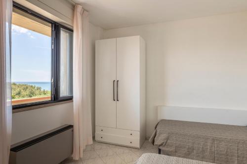 a white bedroom with a bed and a window at Hotel Quisisana in Vada