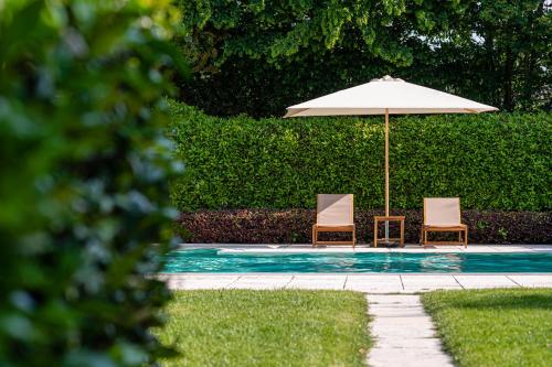 zwei Stühle und ein Sonnenschirm neben einem Pool in der Unterkunft Al Segnavento - Fiori&Frutti in Mestre