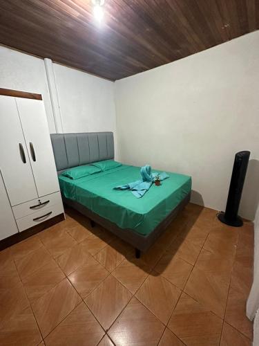 a small room with a green bed and a cabinet at La Casa de Detours Costa Rica in Fortuna