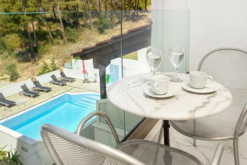 a table with two glasses and chairs next to a pool at Leandros Hotel in Nea Roda