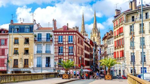 une rue de la ville avec des bâtiments et une église dans l'établissement Hotel Berria, à Hasparren