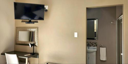 a bathroom with a television on a wall with a sink at Green Kalahari Guesthouse in Upington