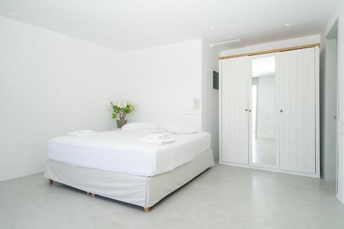 a white bedroom with a white bed and a mirror at Suite Agia Irene Kythnos in Kakóvolon