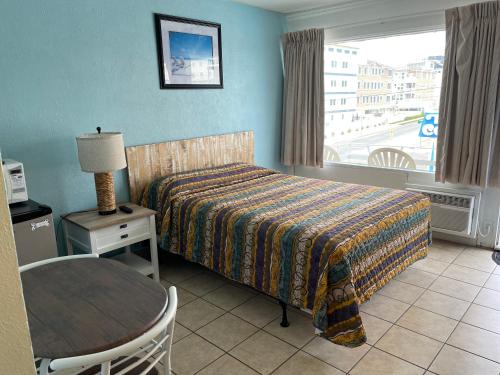 a hotel room with a bed and a table and a window at Beach Colony Motel in Wildwood Crest