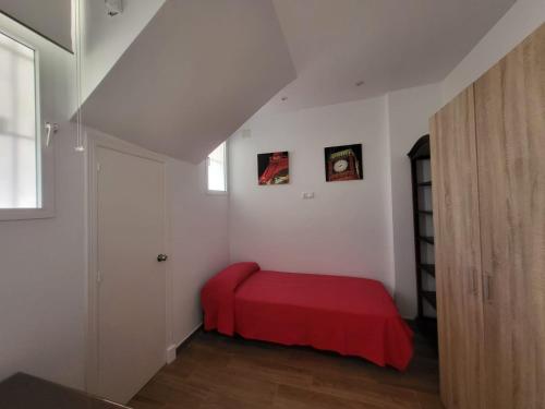 1 dormitorio con 1 cama roja en una habitación blanca en Apartamento Parque Bahía, en Puerto Real