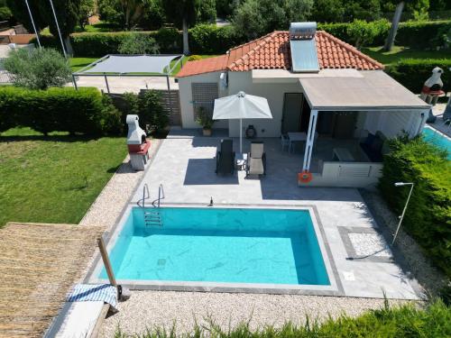 a swimming pool in front of a house at Cypress Garden Villas in Svoronata
