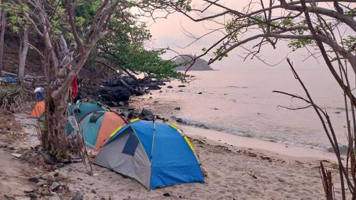two tents on a beach next to the water at Masamirey Endpoint Cottages Rental in Sual