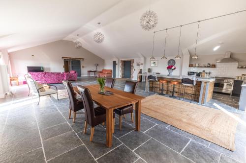 a living room and kitchen with a wooden table and chairs at Gaer Fawr Barns in Guilsfield