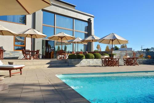 a swimming pool with tables and umbrellas in front of a building at Inca Hoteles in Los Andes
