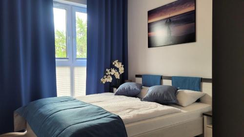 隱海市的住宿－Apartamenty Lambert Ustronie Morskie，一间卧室配有一张带蓝色窗帘的床和一扇窗户