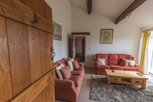a living room with two red couches and a table at Gaer Fawr Barns in Guilsfield