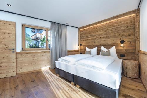 a bedroom with a large white bed with a wooden wall at Chalet Berna in Ortisei